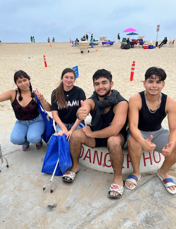 Four SAC ULink students pose on the beach during their beach clean-up volunteer event.